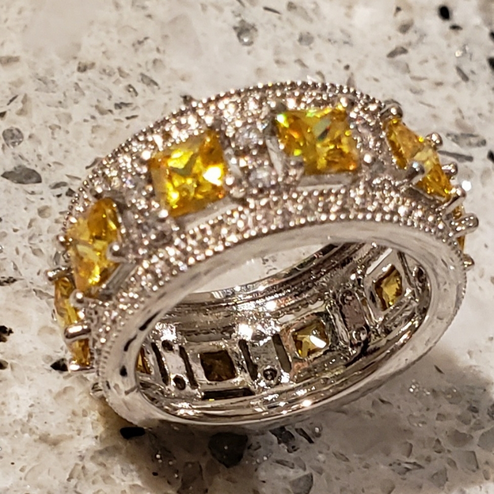 Platinum plated sterling silver band ring with simulated yellow sapphire…